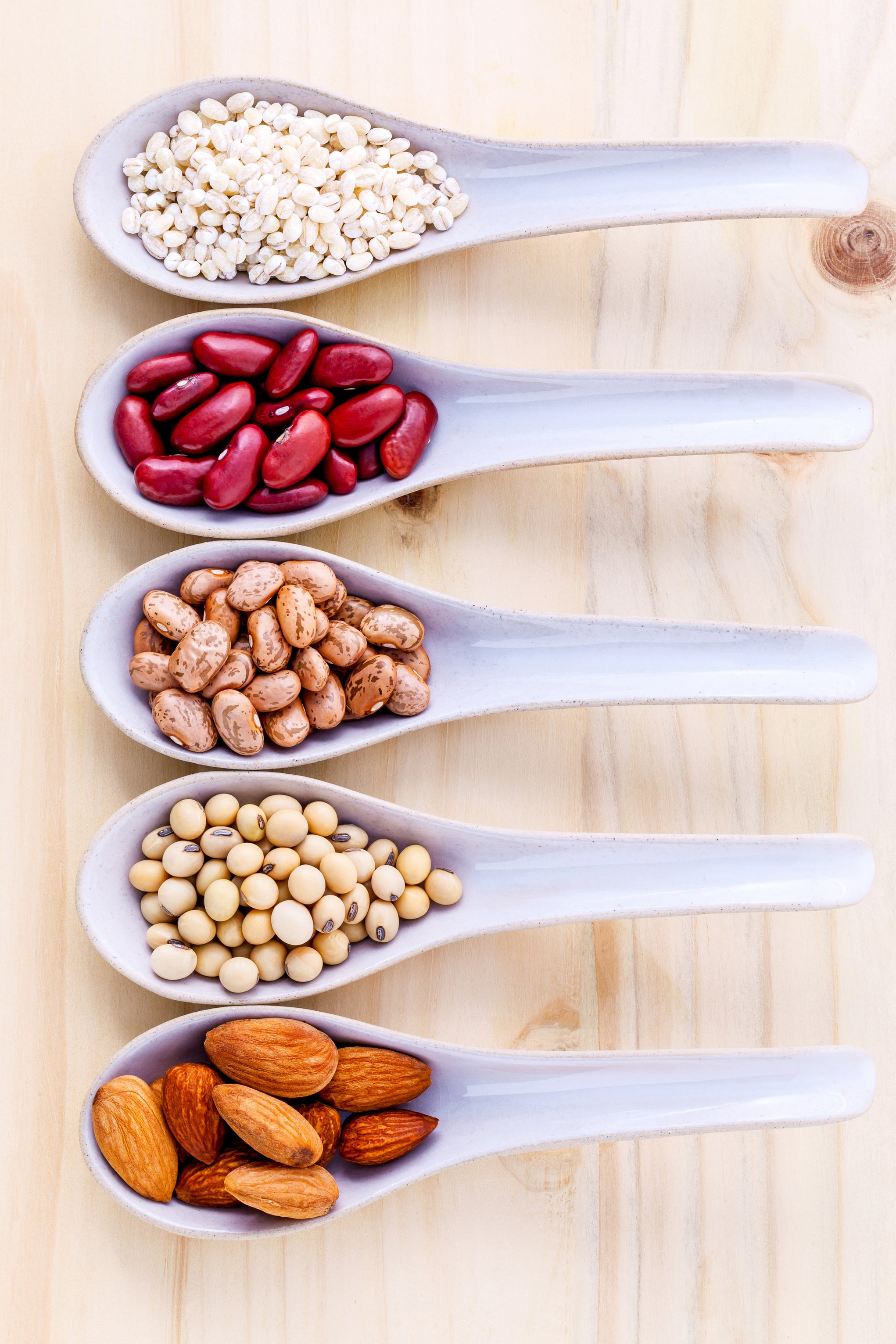 Assortment of beans and lentils in ceramic spoon .